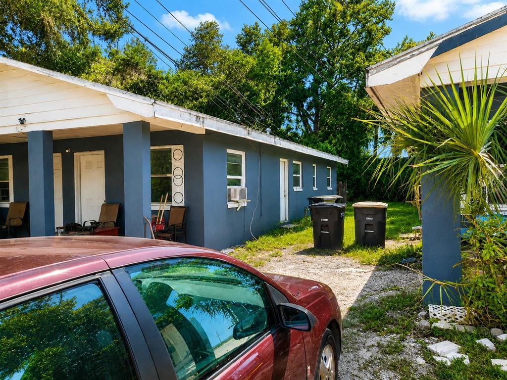 A side view of a gray house with a gravel driveway and two trash cans — 1506 N MADISON AVENUE, CLEARWATER, FL
