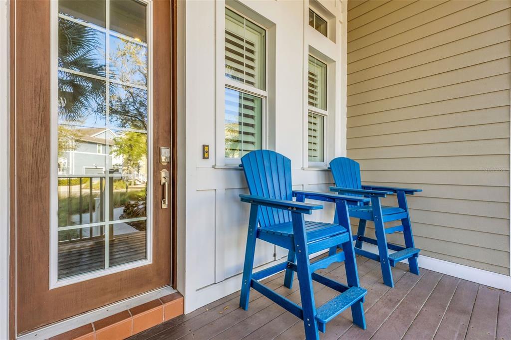 Two blue Adirondack chairs sit on a wooden porch next to a glass-paned door — 289 SAPPHIRE LAKE DRIVE UNIT 202, BRADENTON, FL