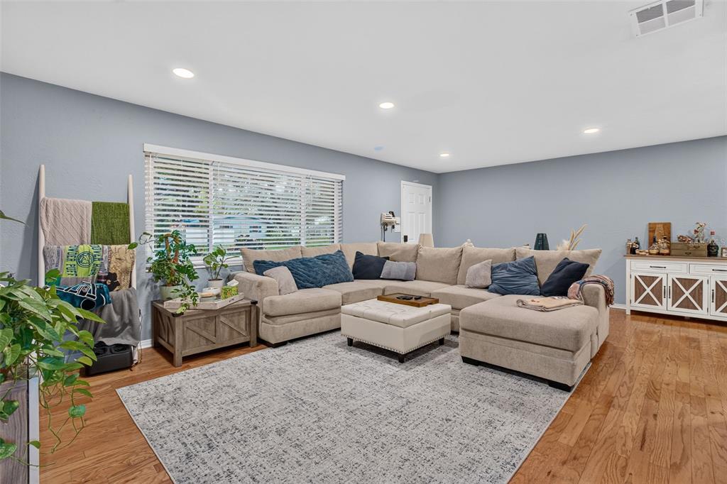 A living room features a large sectional sofa, a patterned area rug, and hardwood floors — 11373 67TH AVENUE, SEMINOLE, FL