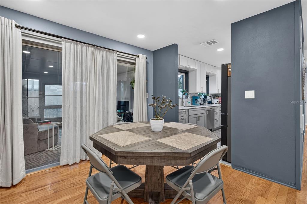 A dining area features an octagonal wooden table, gray chairs, and a view into the kitchen — 11373 67TH AVENUE, SEMINOLE, FL