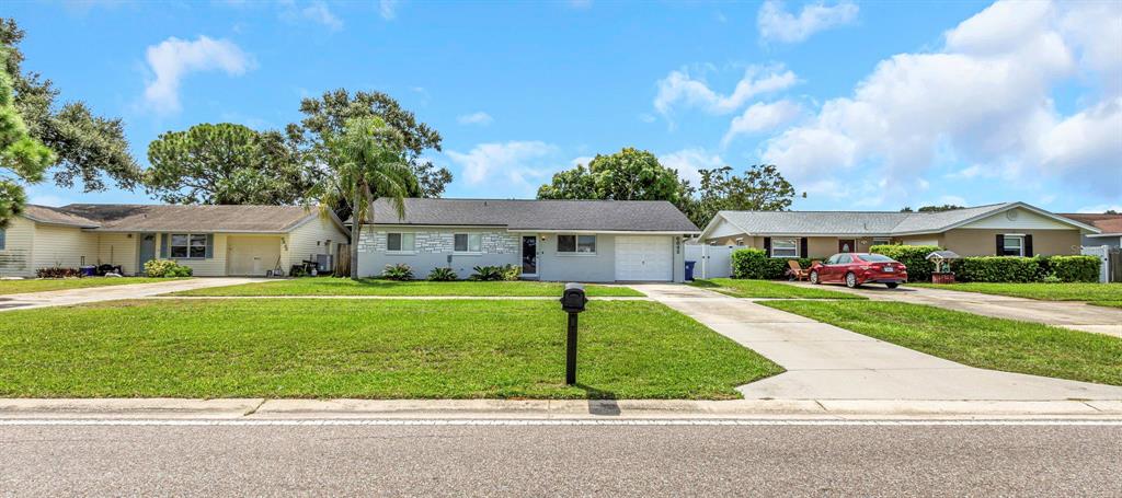 Three single-story suburban houses sit side-by-side with front lawns and concrete driveways — 6842 62ND AVENUE N, PINELLAS PARK, FL