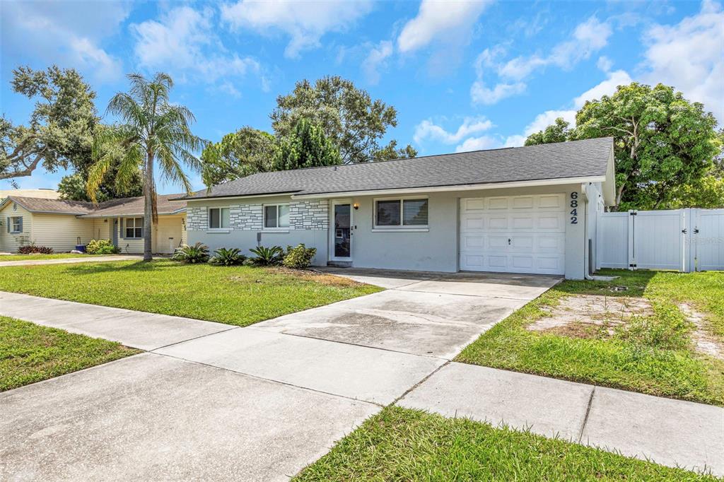 A single-story house with a gray exterior, white garage door, and a concrete driveway — 6842 62ND AVENUE N, PINELLAS PARK, FL