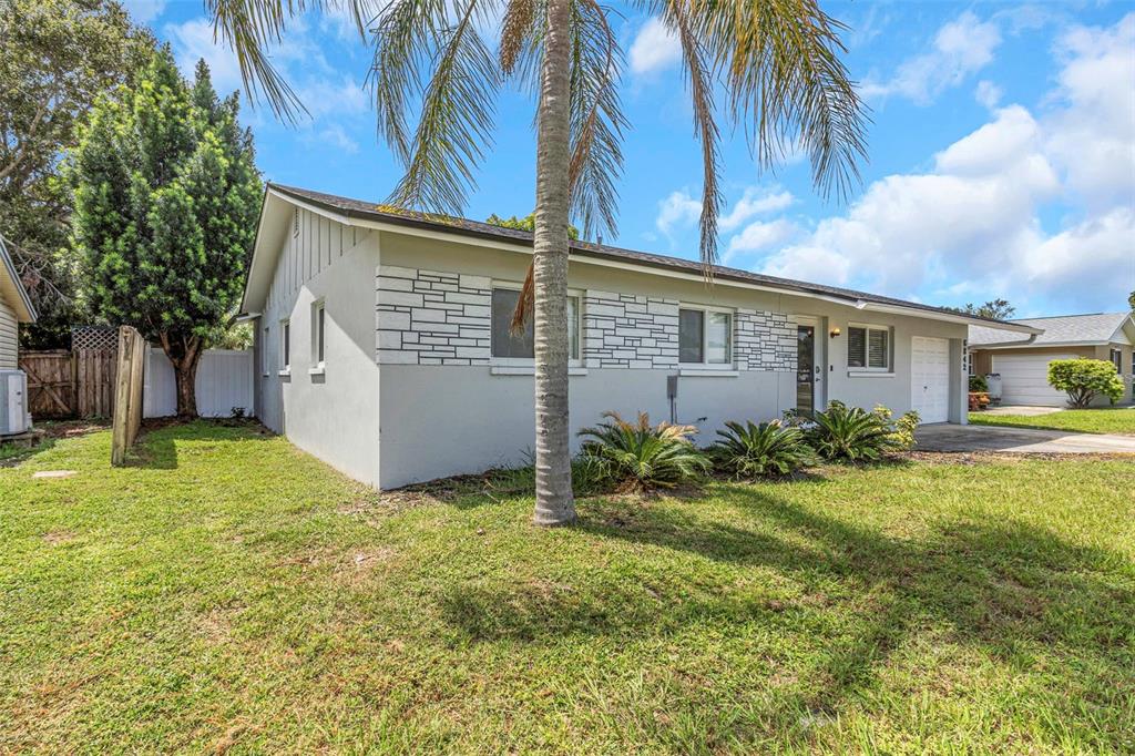 A single-story house with gray stucco walls, stone accents, and a palm tree in front — 6842 62ND AVENUE N, PINELLAS PARK, FL