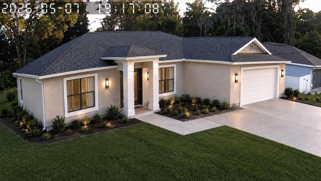A single-story house with a beige stucco exterior, dark roof, and a concrete driveway — 3548 SE 135TH LANE, SUMMERFIELD, FL