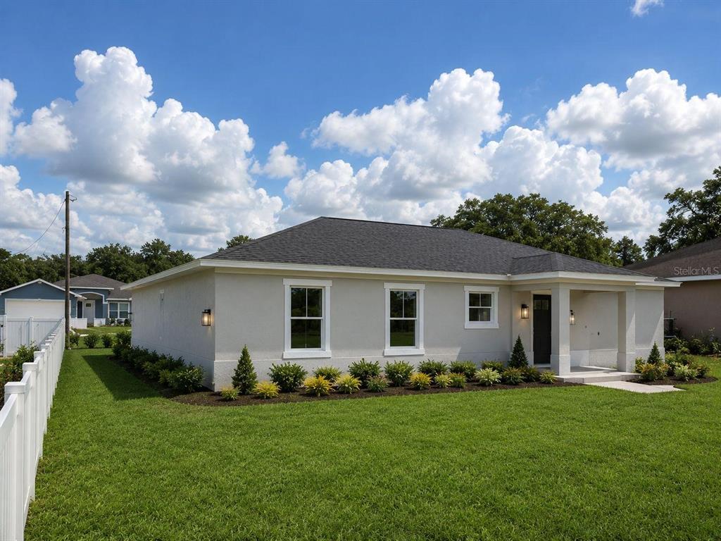 A single-story house with light-colored stucco siding, a dark shingled roof, and a front porch — 3548 SE 135TH LANE, SUMMERFIELD, FL