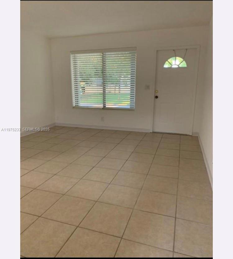 This room features light-colored tile flooring, white walls, a window with blinds, and a door — 401 SW 8th St # A, Hallandale Beach FL 33009, HALLANDALE BEACH, FL