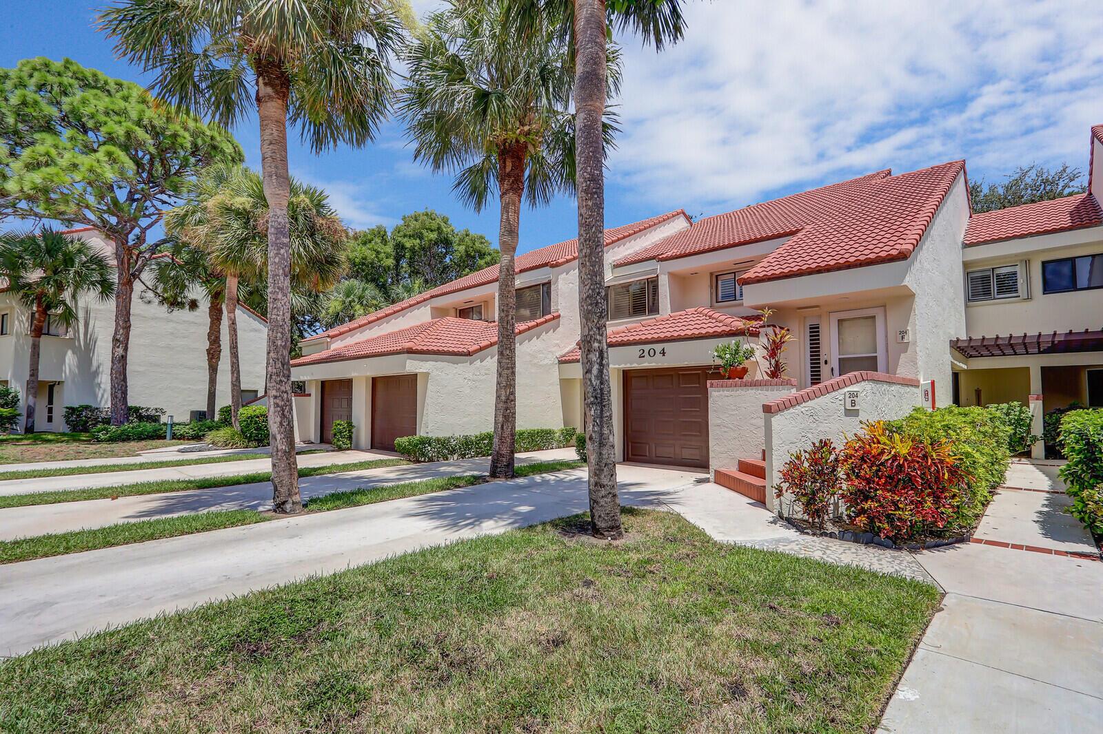 A multi-unit residential building with a red tile roof, palm trees, and concrete driveways — 204 Sea Oats Drive # F, Juno Beach FL 33408, JUNO BEACH, FL