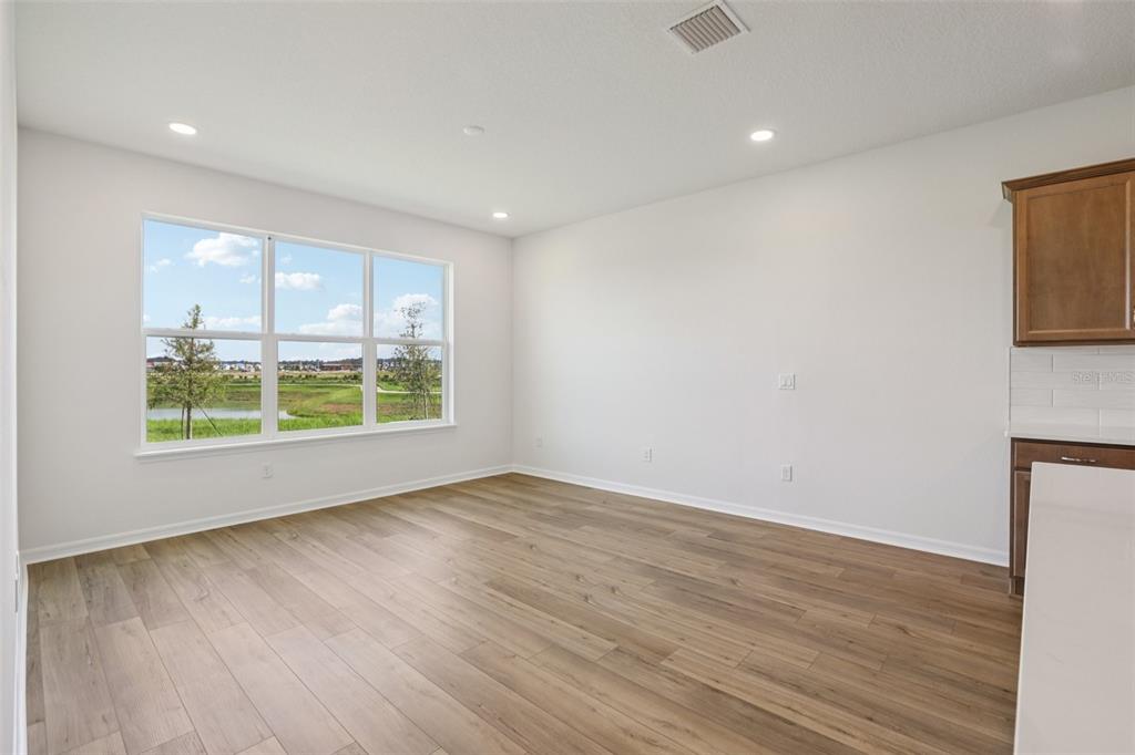 An empty room with wood-look flooring, white walls, recessed lighting, and a large window view — 31455 SPANISH MISSION ROAD, SAN ANTONIO, FL