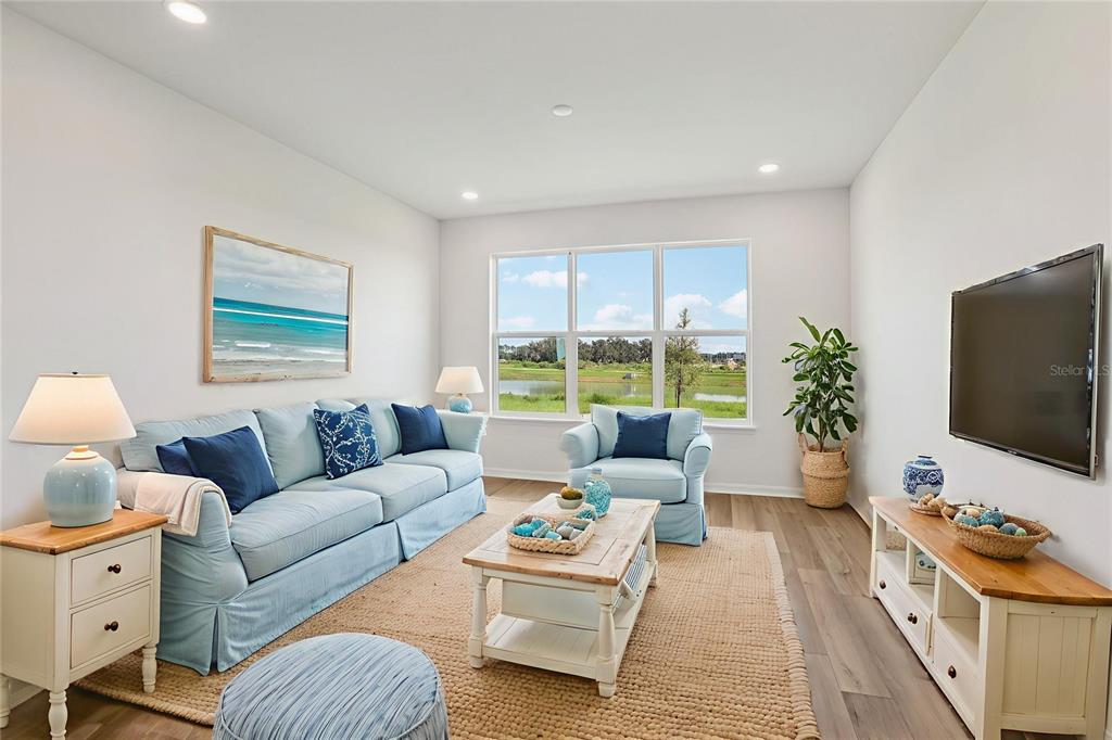 A living room features a light blue sofa, matching armchair, wood coffee table, and television — 31455 SPANISH MISSION ROAD, SAN ANTONIO, FL