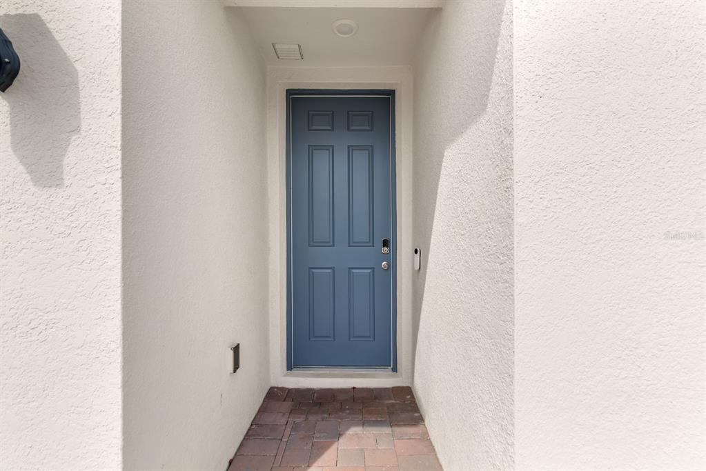 A blue front door is set within a recessed entryway with light-colored stucco walls — 1158 FORESHORE LANE, HAINES CITY, FL