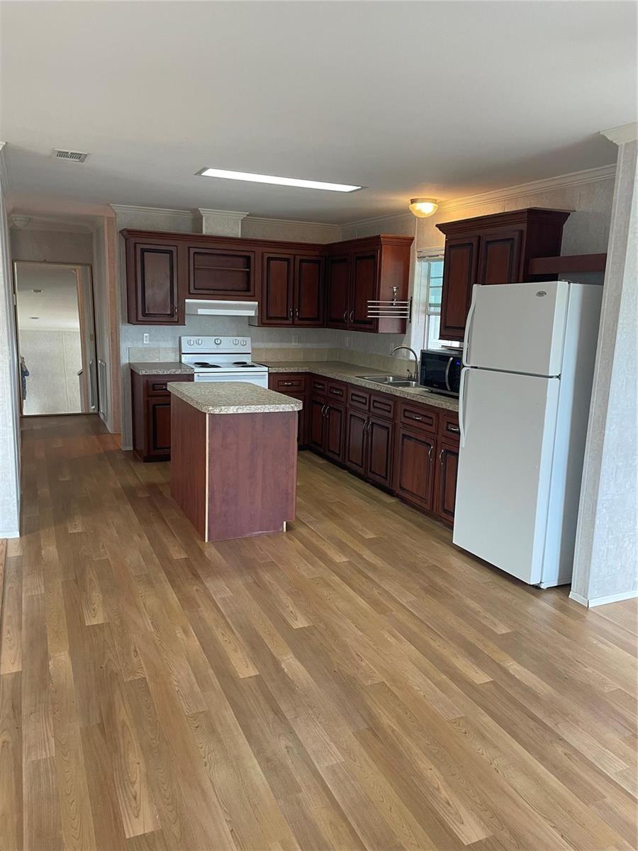 A kitchen features dark wood cabinets, a central island, and a white refrigerator — 2321 SW 85th Avenue, Davie FL 33324, DAVIE, FL