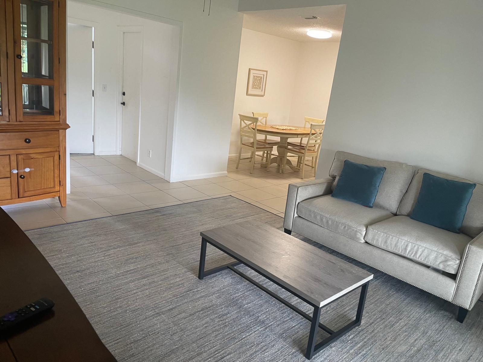 A living room with a gray sofa, coffee table, and area rug near a dining area — 12726 Spinnaker Lane, Wellington FL 33414, WELLINGTON, FL