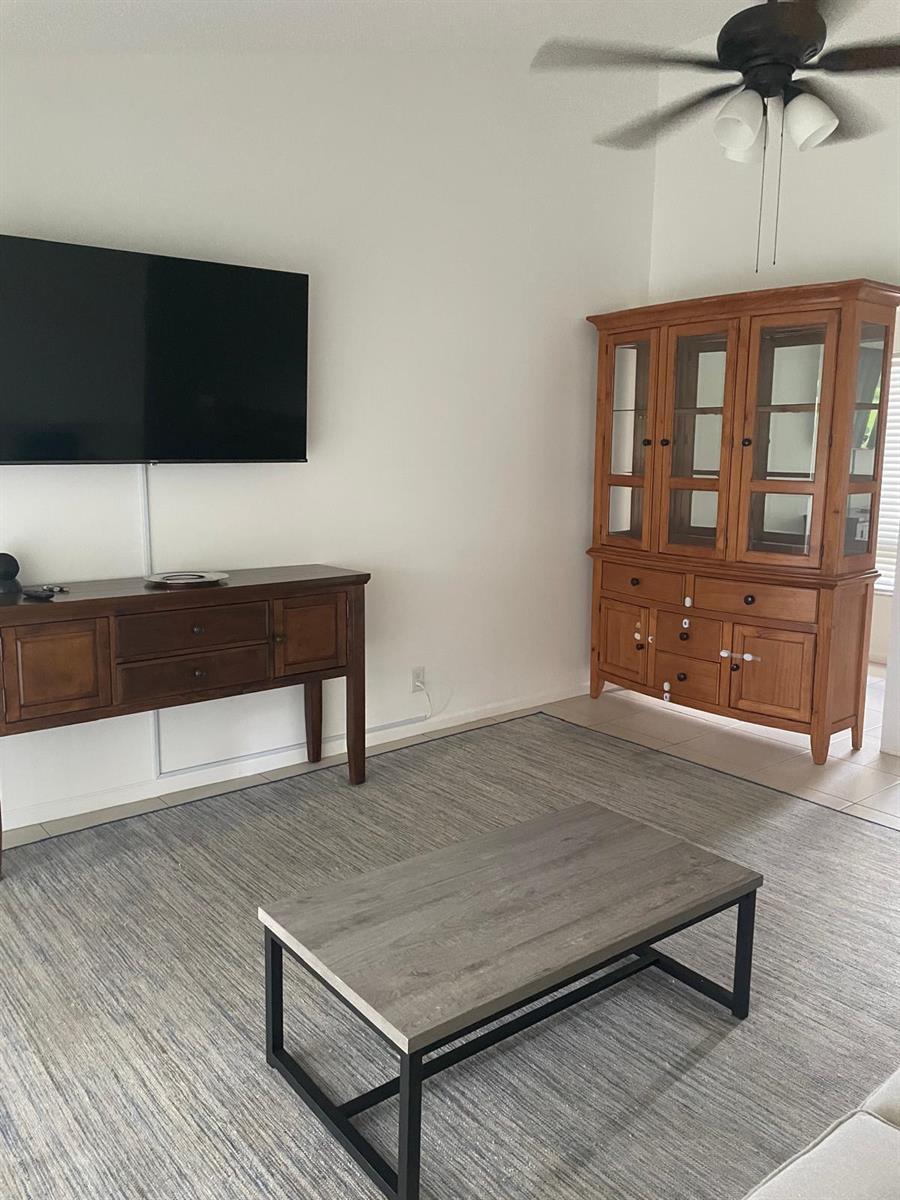 A living room features a wall-mounted television, a wooden sideboard, a hutch, and a coffee table — 12726 Spinnaker Lane, Wellington FL 33414, WELLINGTON, FL