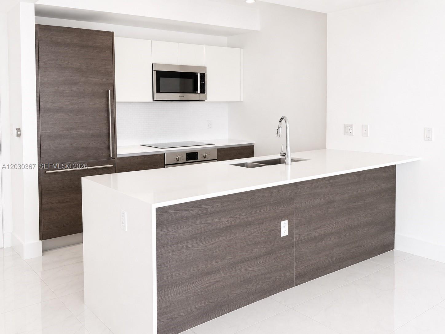 A modern kitchen features a large island, dark wood cabinetry, white countertops, and stainless appliances — 301 Altara Ave # 529, Coral Gables FL 33146, CORAL GABLES, FL