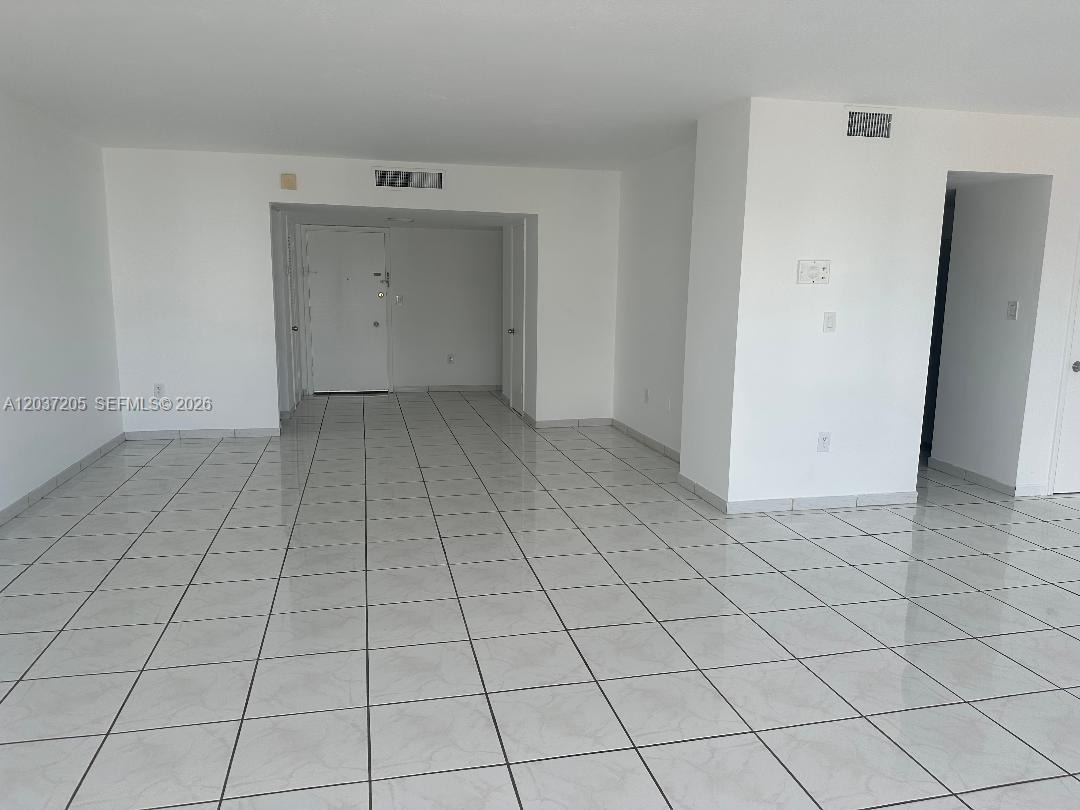 An empty room features white walls, a white door, and light-colored tiled flooring — 1075 92nd St # 603, Bay Harbor Islands FL 33154, BAY HARBOR ISLANDS, FL