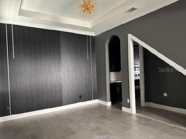 A room with gray tile floors, a dark vertical-slatted accent wall, and a tray ceiling — 12518 BOVET AVENUE, ORLANDO, FL