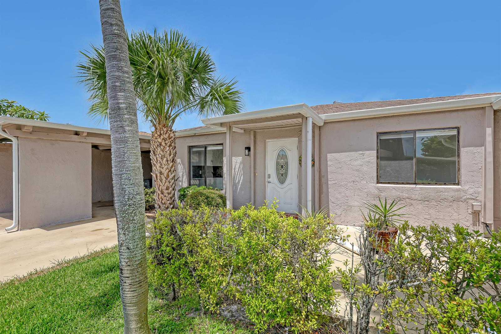 A single-story house exterior features a white front door, a palm tree, and landscaping — 14735 Wildflower Lane, Delray Beach FL 33446, DELRAY BEACH, FL