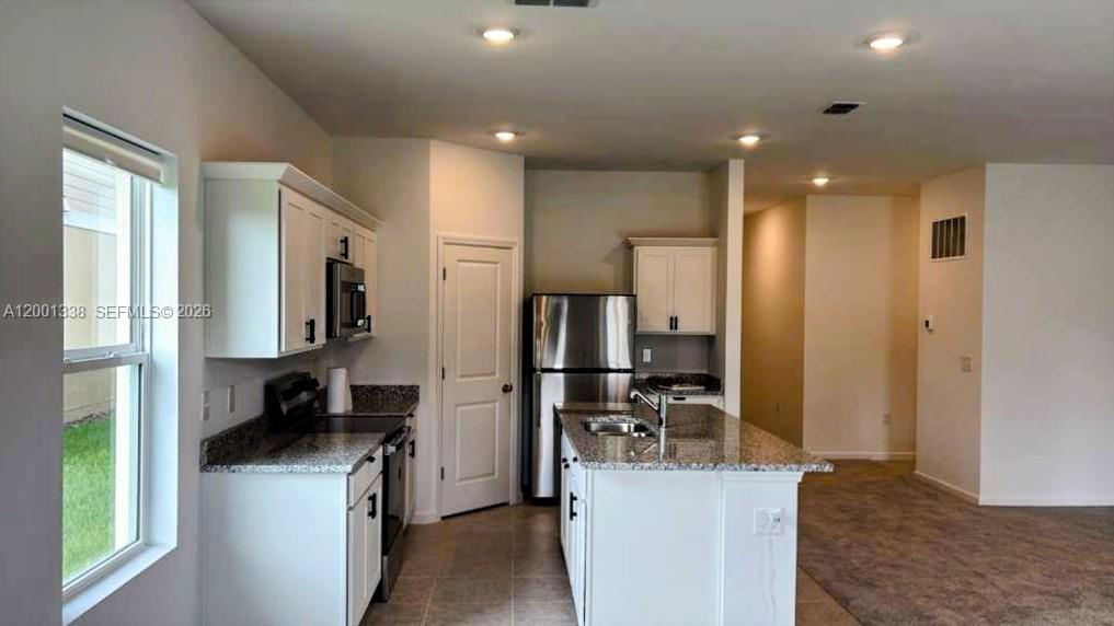 A kitchen features white cabinets, granite countertops, stainless steel appliances, and an island — KISSIMMEE, FL