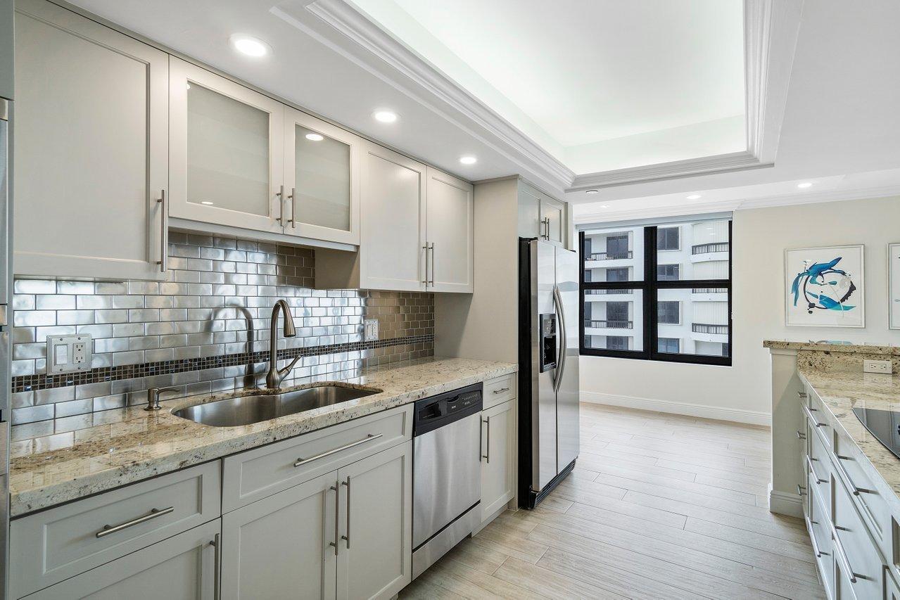 A kitchen with light gray cabinets, granite countertops, a stainless steel sink, and subway tile backsplash — 3115 S Ocean Boulevard # 1001, Highland Beach FL 33487, HIGHLAND BEACH, FL