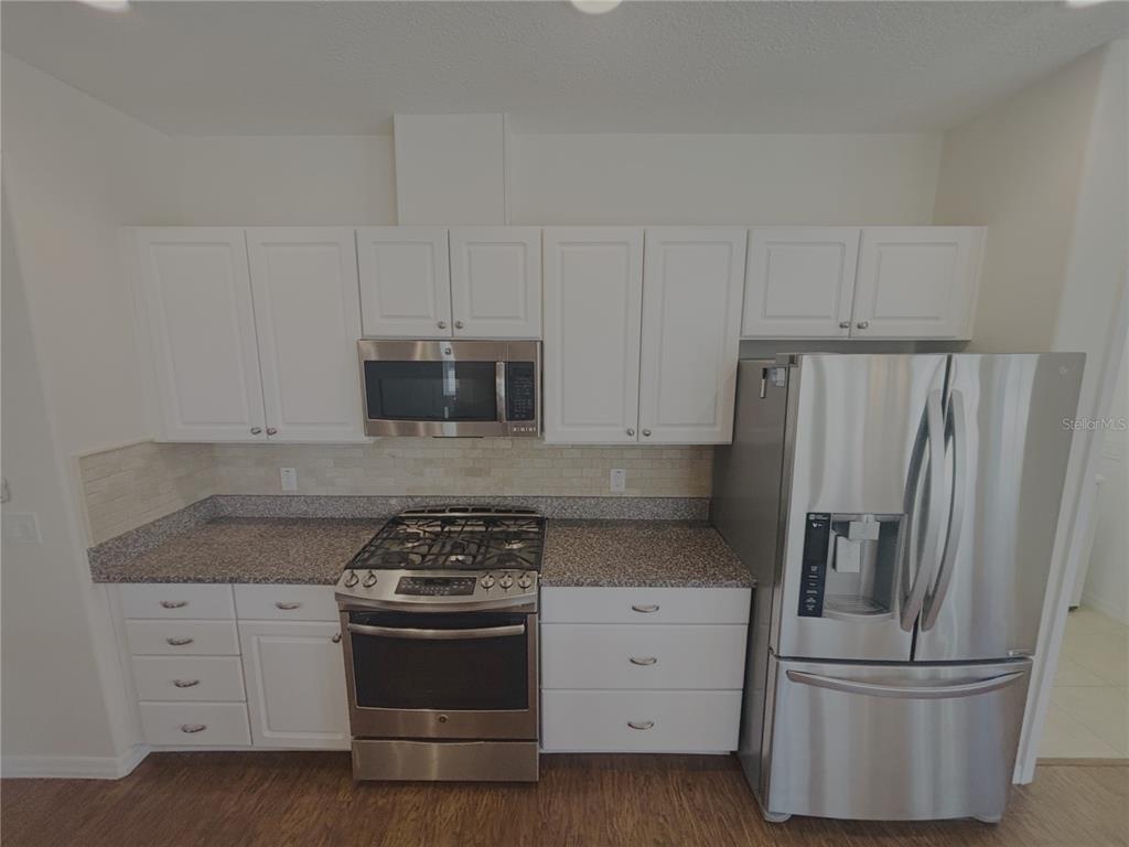 A kitchen features white cabinets, stainless steel appliances, and granite countertops — 4859 NW 35TH LANE ROAD, OCALA, FL