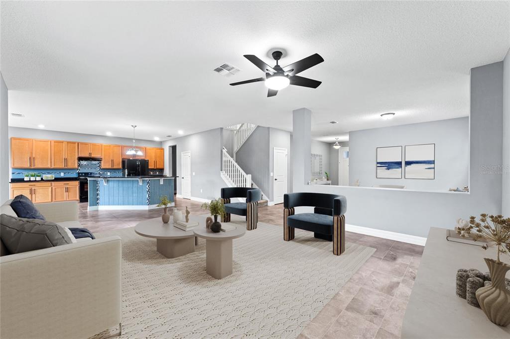 This is a virtually staged living room with a kitchen and staircase in the background — 14505 WARD ROAD, ORLANDO, FL