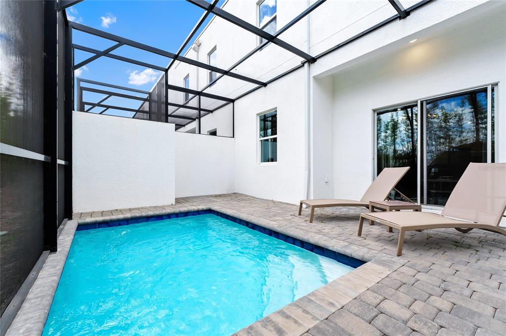 A small rectangular swimming pool sits on a paved patio enclosed by a screened lanai — 344 FAMAGUSTA DR DRIVE, DAVENPORT, FL