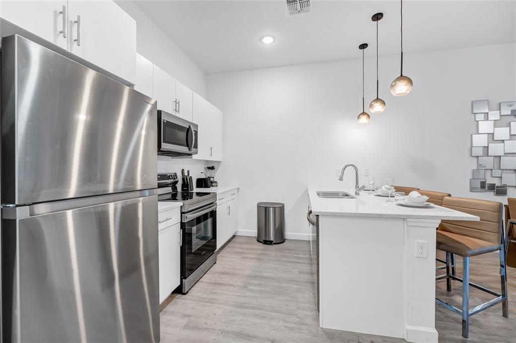 A modern kitchen features white cabinets, stainless steel appliances, and a white quartz island — 344 FAMAGUSTA DR DRIVE, DAVENPORT, FL