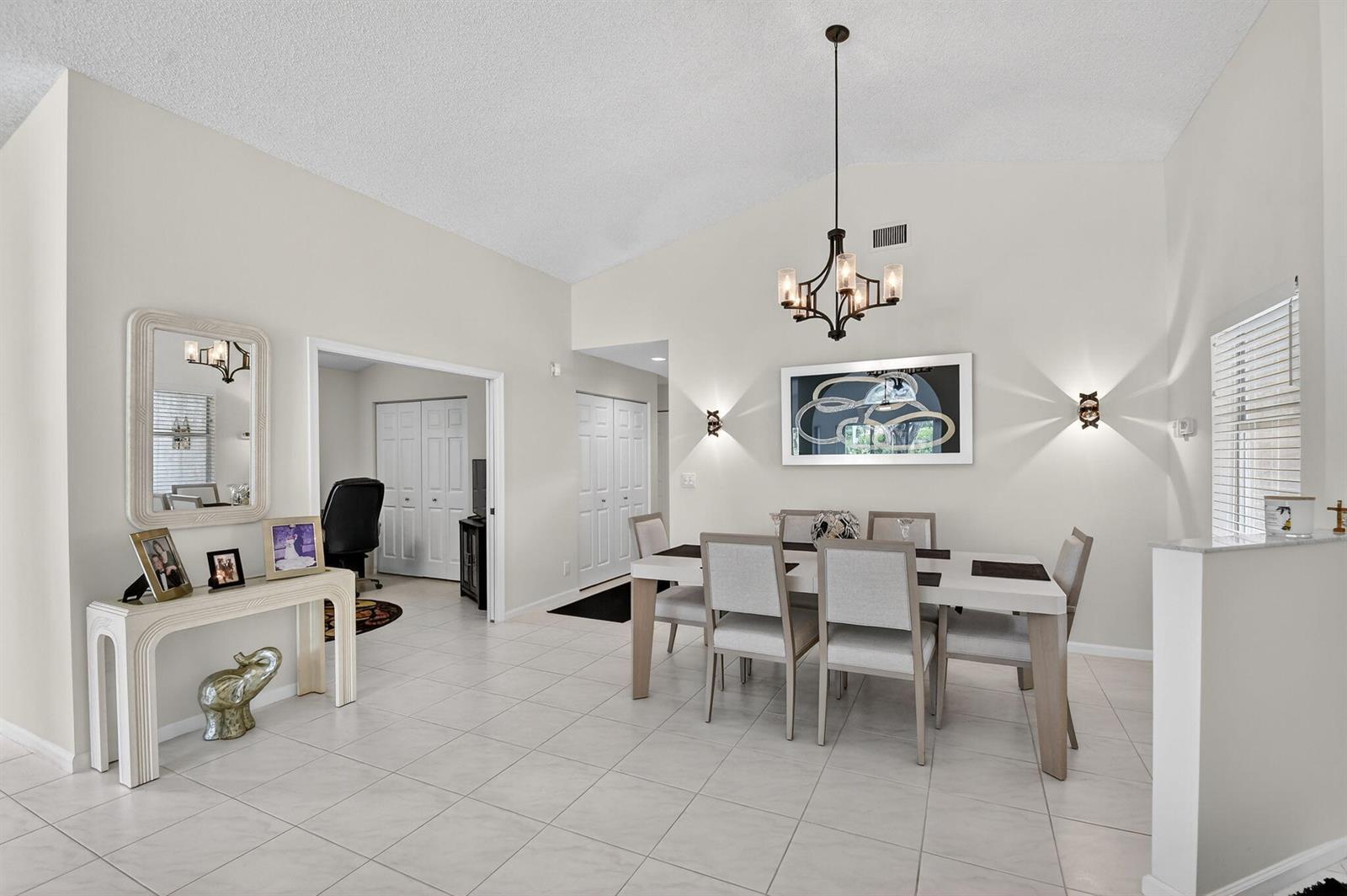 A dining room with a vaulted ceiling, tile floors, a chandelier, and a console table — 9718 Harbour Lake Circle, Boynton Beach FL 33437, BOYNTON BEACH, FL