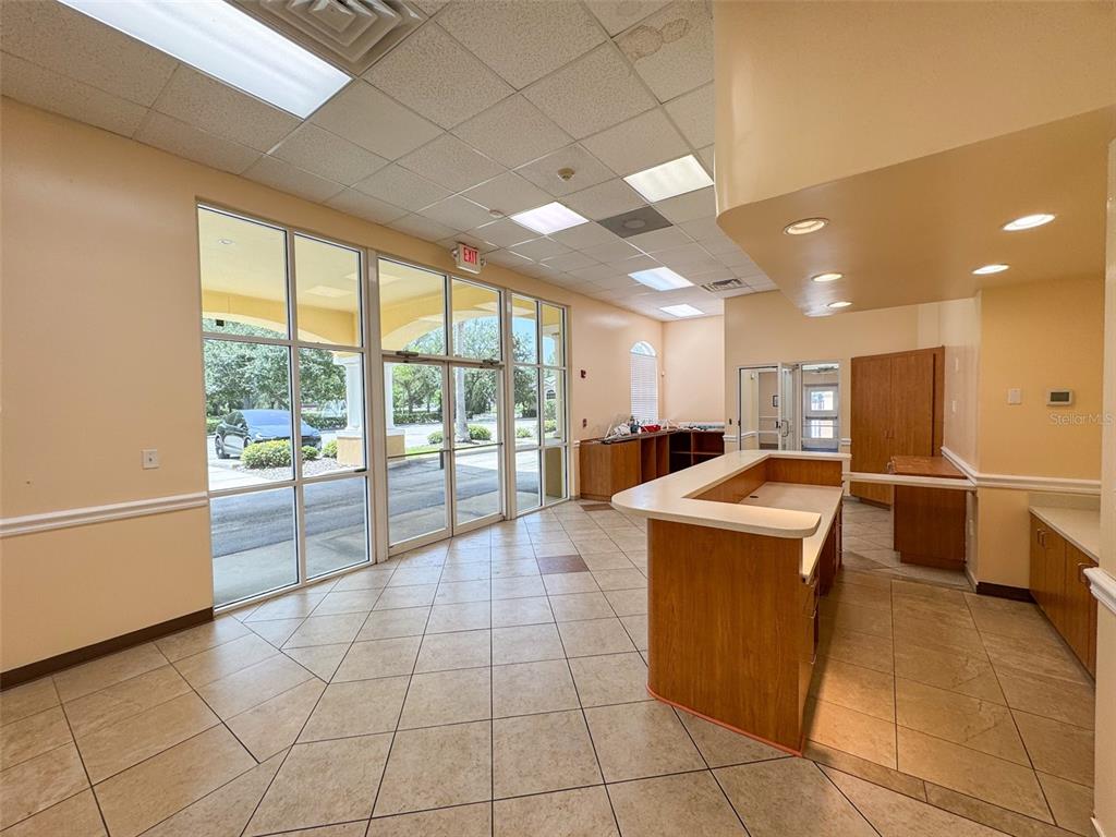 A commercial interior features a reception desk, tile flooring, large windows, and drop ceiling panels — 690 LAKE FOREST BOULEVARD UNIT Suite 1, SANFORD, FL