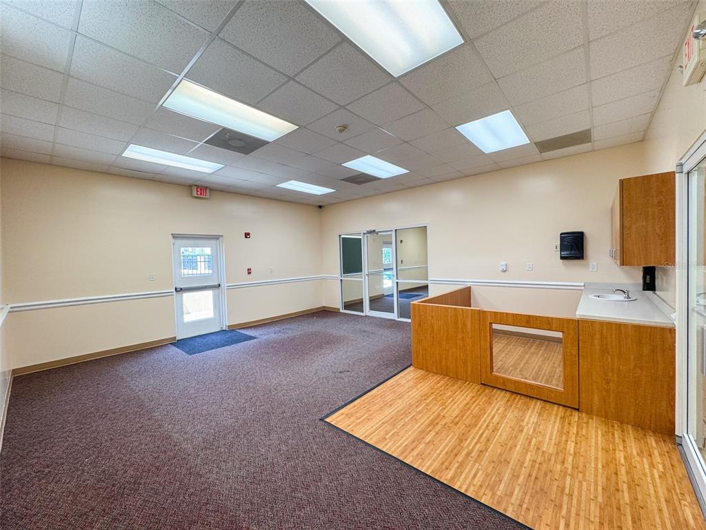 An office space features a carpeted area, a wood-paneled partition, and a small sink — 690 LAKE FOREST BOULEVARD UNIT Suite 1, SANFORD, FL