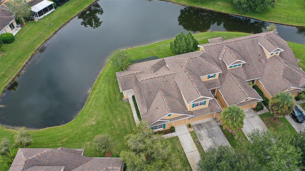 A two-story duplex with tan siding, blue shutters, two garages, and a front lawn — 20312 NOBLE OAK PLACE, TAMPA, FL