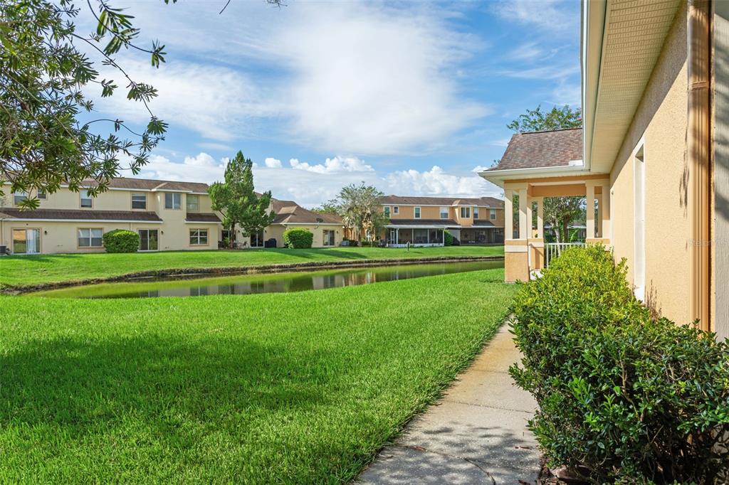 A view of a grassy lawn, a small pond, and multi-story residential buildings — 20312 NOBLE OAK PLACE, TAMPA, FL