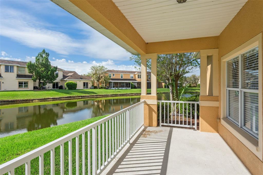 A covered patio with a white railing overlooks a small pond and neighboring houses — 20312 NOBLE OAK PLACE, TAMPA, FL