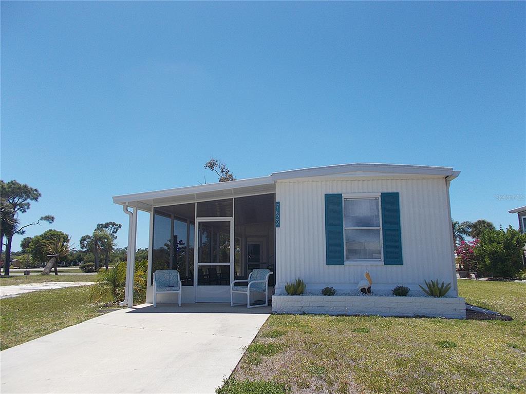 A white mobile home features a screened-in front porch, teal shutters, and a concrete driveway — 7622 SILAGE CIRCLE, PORT CHARLOTTE, FL