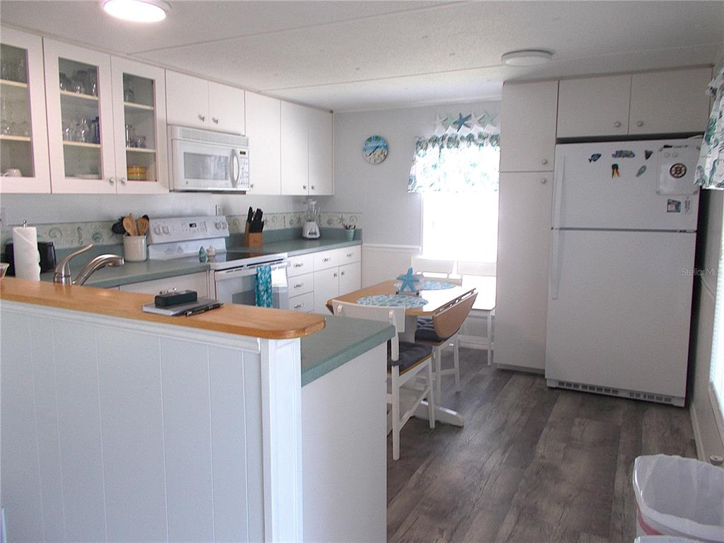 A kitchen with white cabinets, light countertops, a dining table, and a white refrigerator — 7622 SILAGE CIRCLE, PORT CHARLOTTE, FL