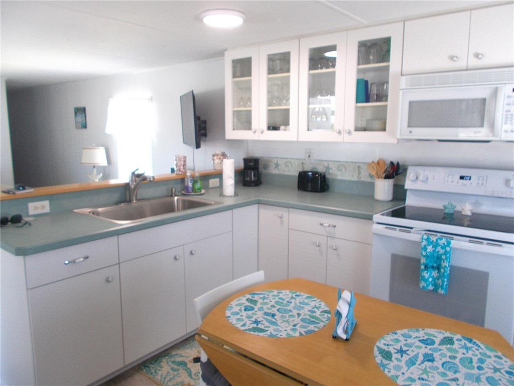 A kitchen with white cabinets, teal countertops, and a dining table with patterned placemats — 7622 SILAGE CIRCLE, PORT CHARLOTTE, FL