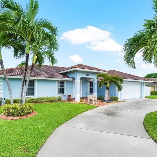 A light blue single-story house with a tiled roof, palm trees, and a concrete driveway — 1906 N N A St Street, FL 33460, FL
