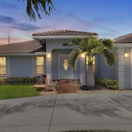 A light blue house exterior features a tiled roof, a palm tree, and a front entrance — 1906 N N A St Street, FL 33460, FL