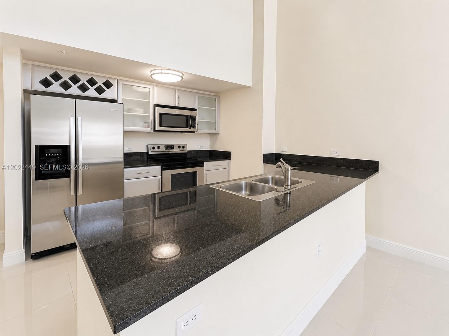 A kitchen features stainless steel appliances, dark granite countertops, and white cabinetry — 1871 NW S River Dr # A04, Miami FL 33125, MIAMI, FL