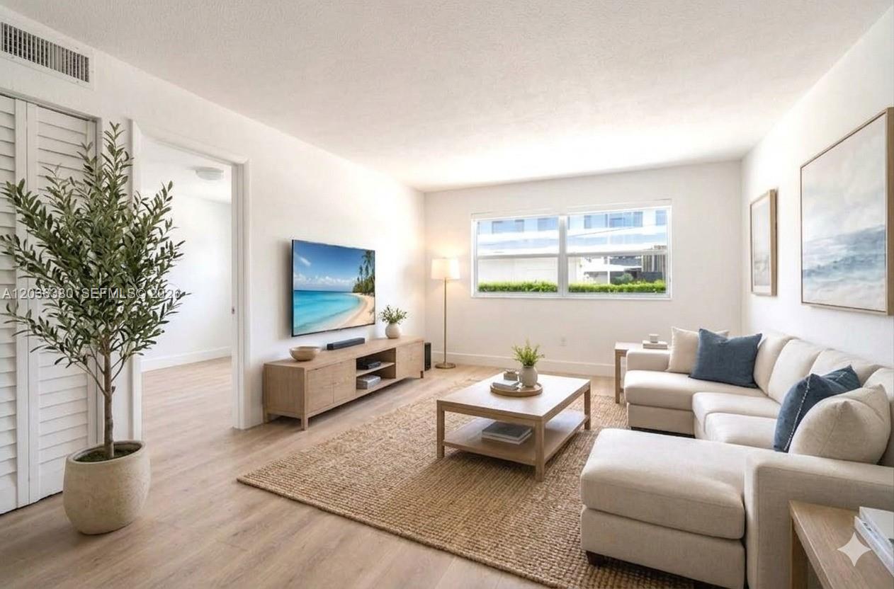A bright living room features a sectional sofa, a television, and light wood flooring — 444 SW 4th St # 204, Miami FL 33130, MIAMI, FL