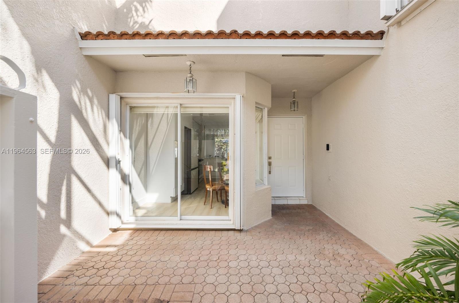 A paved patio leads to a sliding glass door and a white entry door — 10233 NW 52nd Ln, Doral FL 33178, DORAL, FL