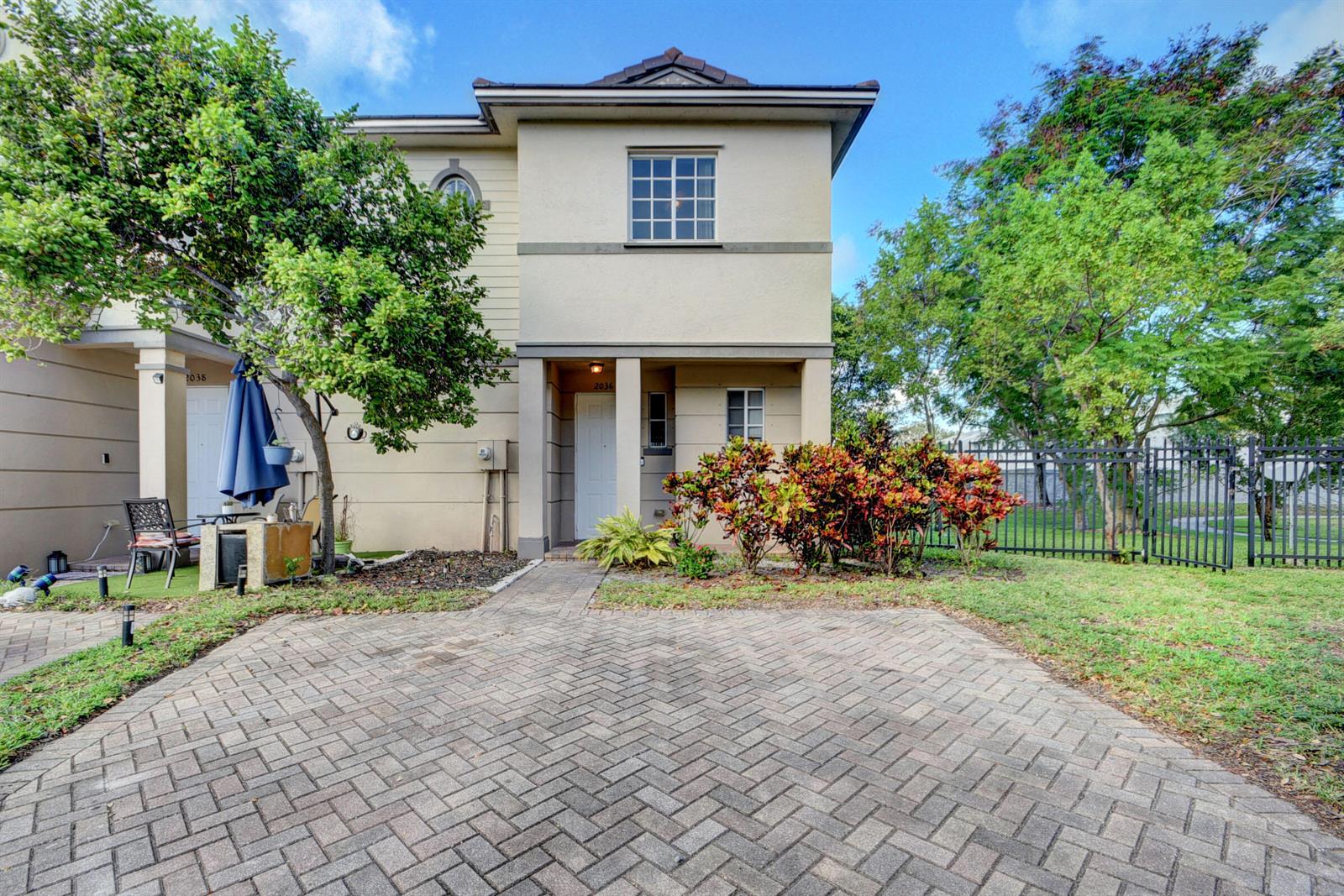 A two-story beige townhouse with a brick paver driveway and a small front garden — 2036 Marsh Harbor Drive, West Palm Beach FL 33404, WEST PALM BEACH, FL