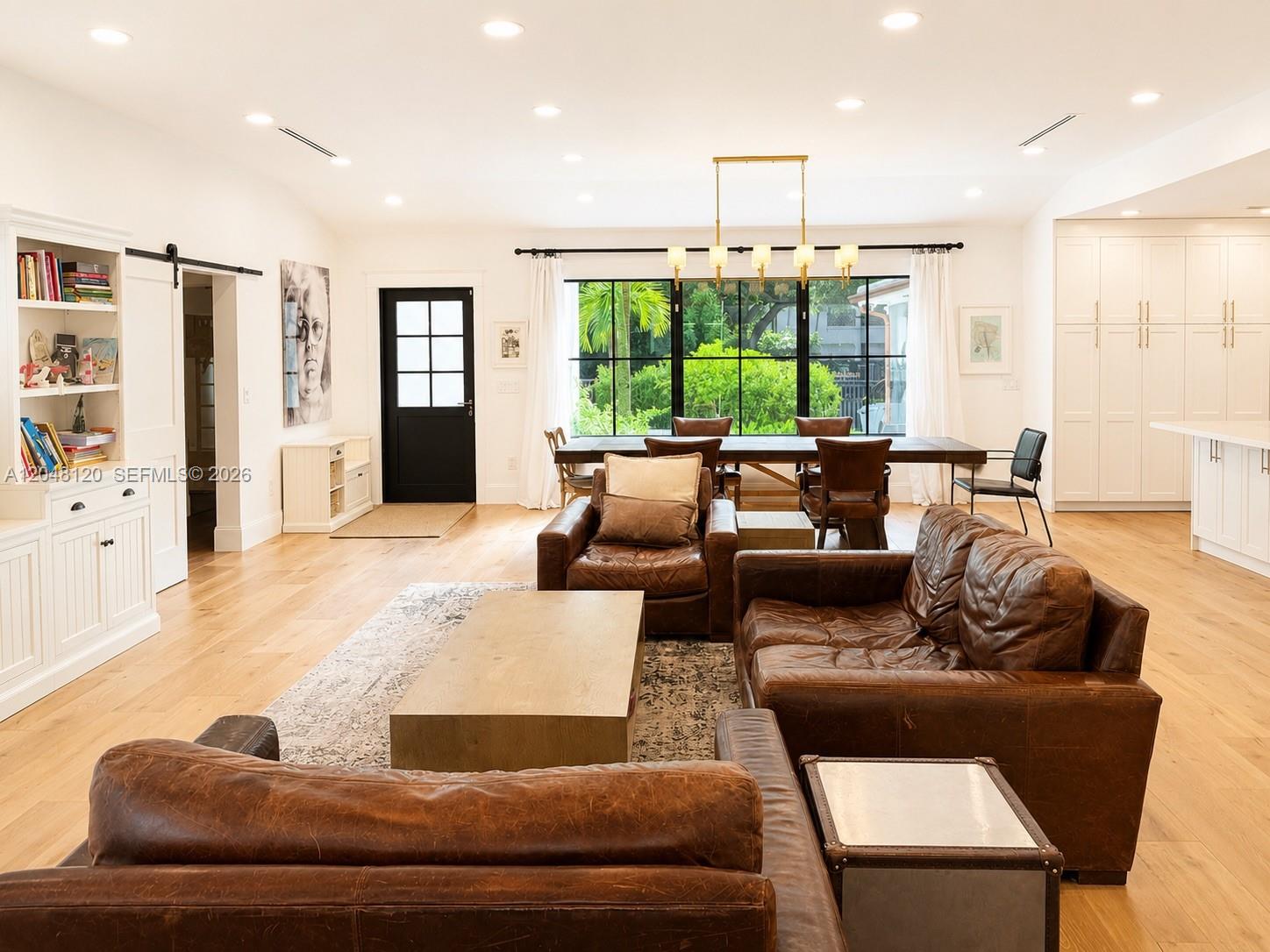 A living and dining area features leather sofas, a wooden coffee table, and large windows — 4455 N Bay Rd, Miami Beach FL 33140, MIAMI BEACH, FL