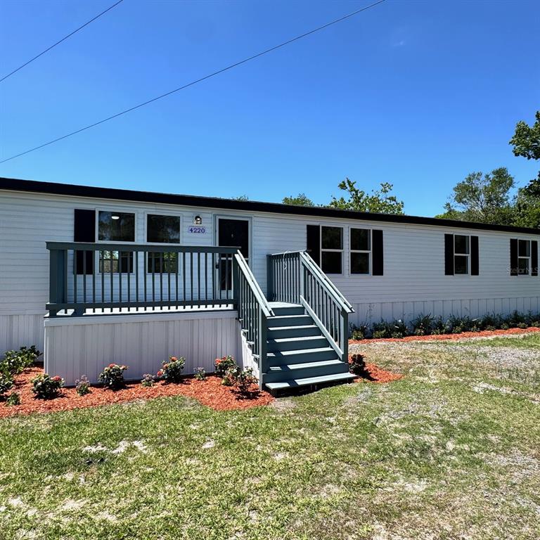 A single-story mobile home with white siding, dark shutters, and a wooden front deck — 4220 OLD DIXIE HIGHWAY, AUBURNDALE, FL