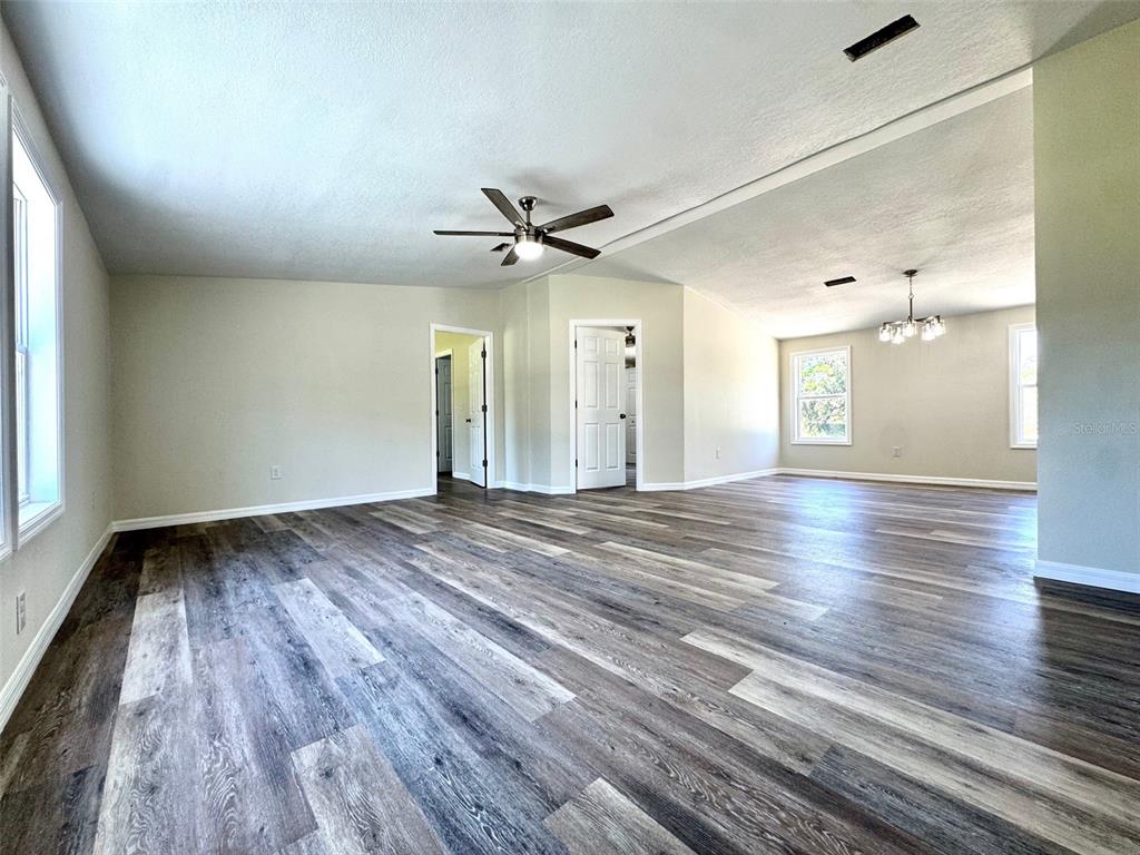 A spacious living area features light-colored walls, a ceiling fan, and wood-look vinyl flooring — 4220 OLD DIXIE HIGHWAY, AUBURNDALE, FL