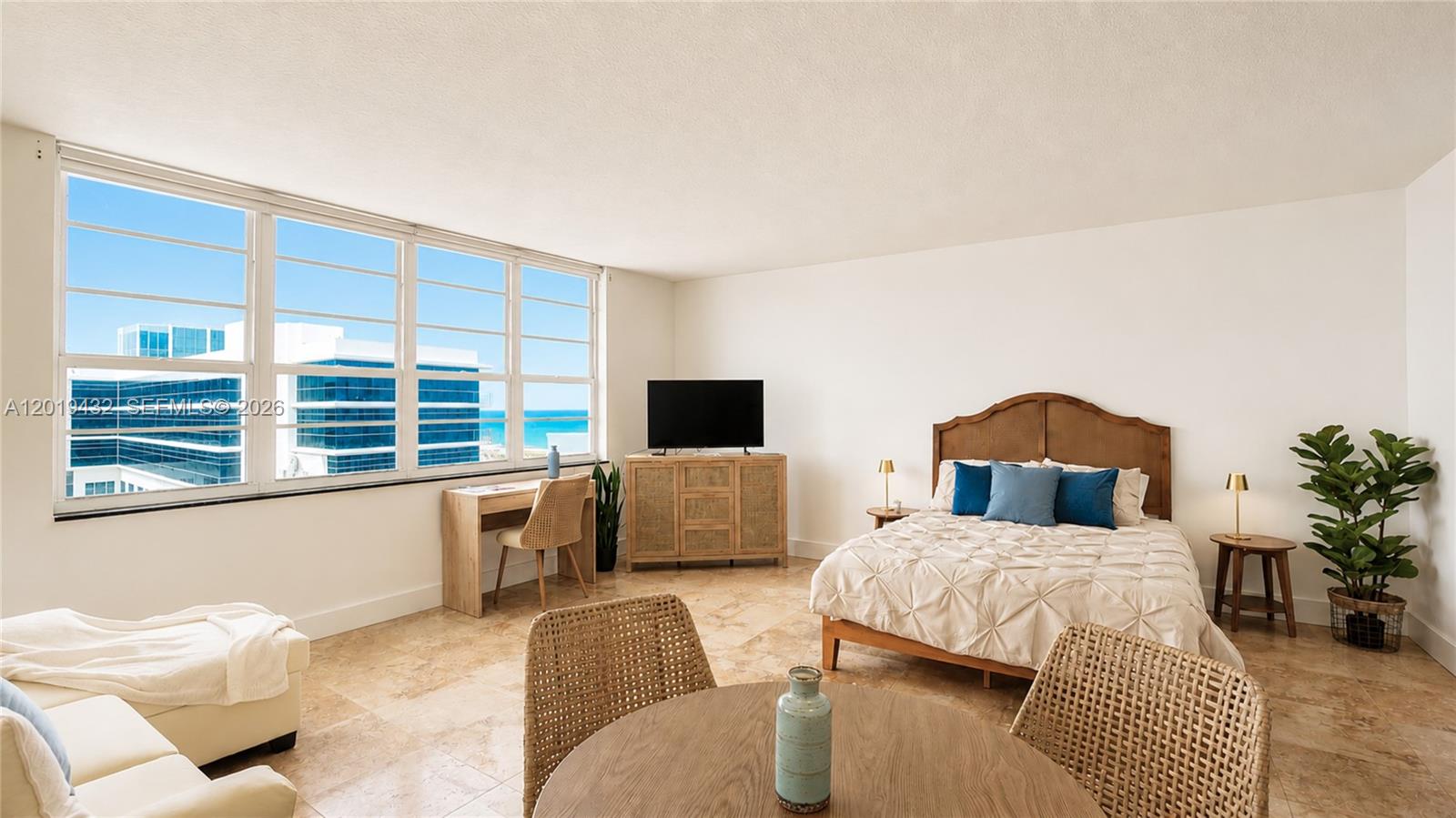 A bedroom with a bed, desk, and dining table features large windows overlooking the ocean — 100 Lincoln Rd # 1206, Miami Beach FL 33139, MIAMI BEACH, FL