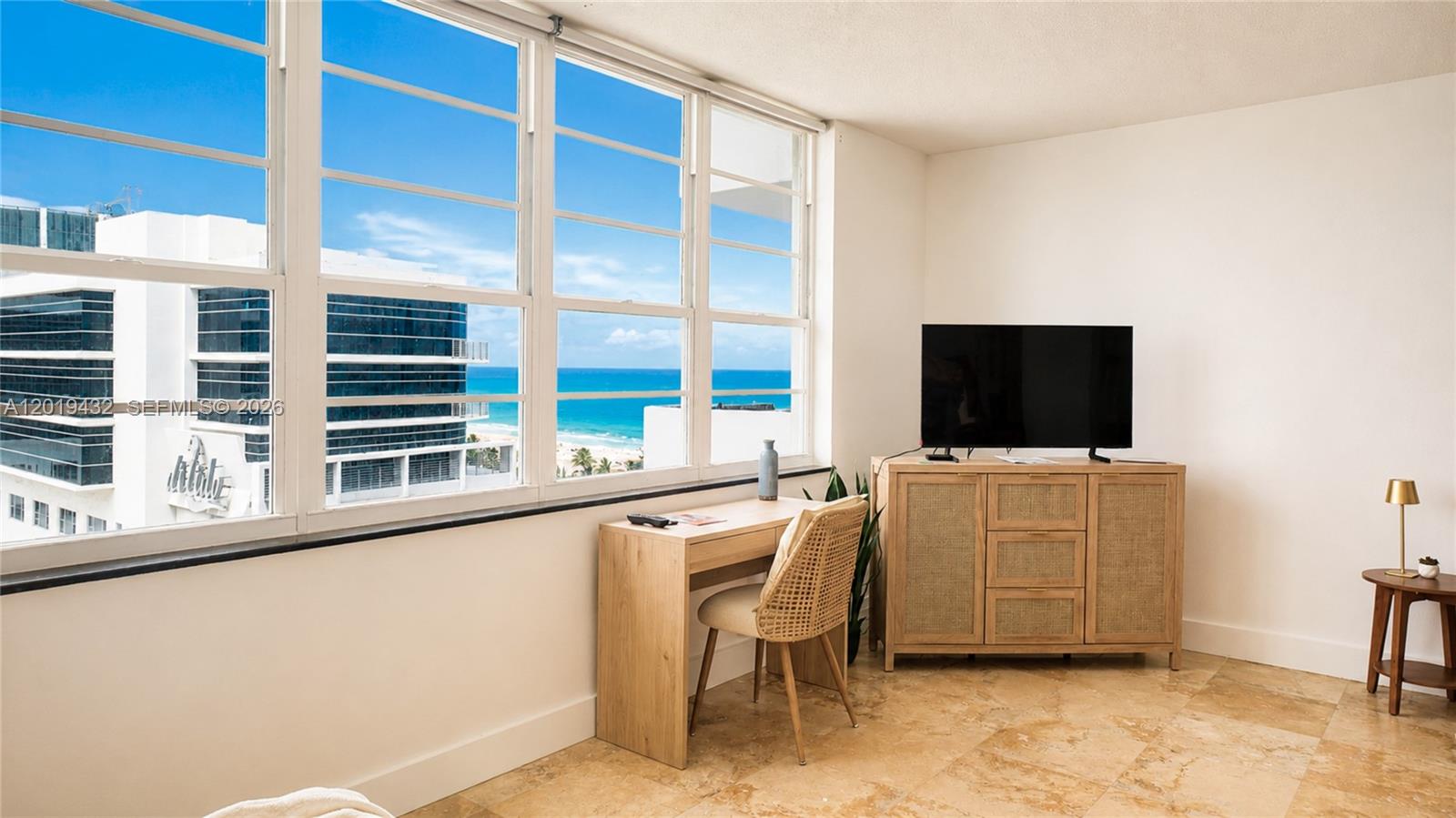 A room with tile floors, a desk, a television console, and large windows overlooking the ocean — 100 Lincoln Rd # 1206, Miami Beach FL 33139, MIAMI BEACH, FL