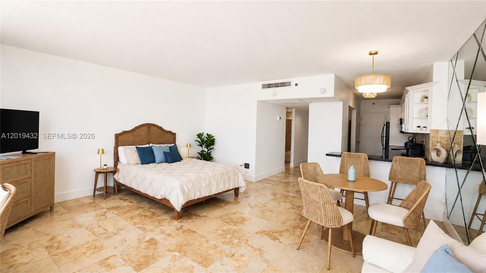A studio apartment features a bed, dining set, and kitchen with light tile flooring — 100 Lincoln Rd # 1206, Miami Beach FL 33139, MIAMI BEACH, FL