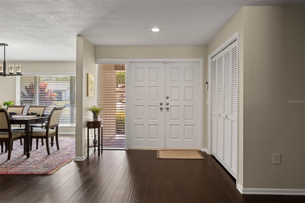 A foyer with dark wood flooring, a white double door, and a louvered closet door — 13916 MIDDLE PARK DRIVE, TAMPA, FL