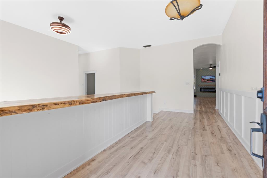 A room with light wood flooring, a live-edge wood bar, and white wainscoting — 512 CAULDER PARK ROAD, SEFFNER, FL
